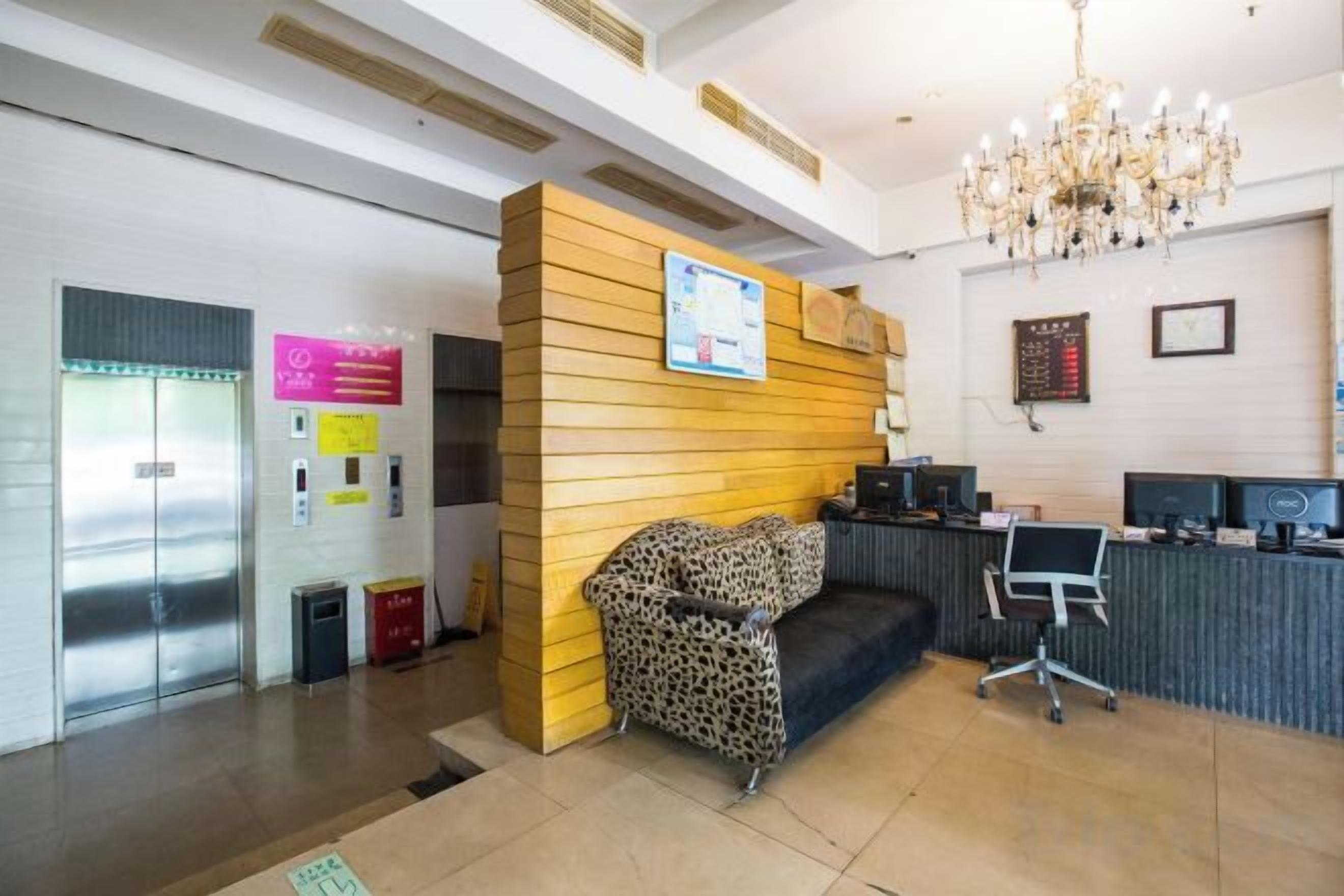 A reception area with a reception desk, a waiting area with a sofa, a chandelier, and a wall-mounted information board.