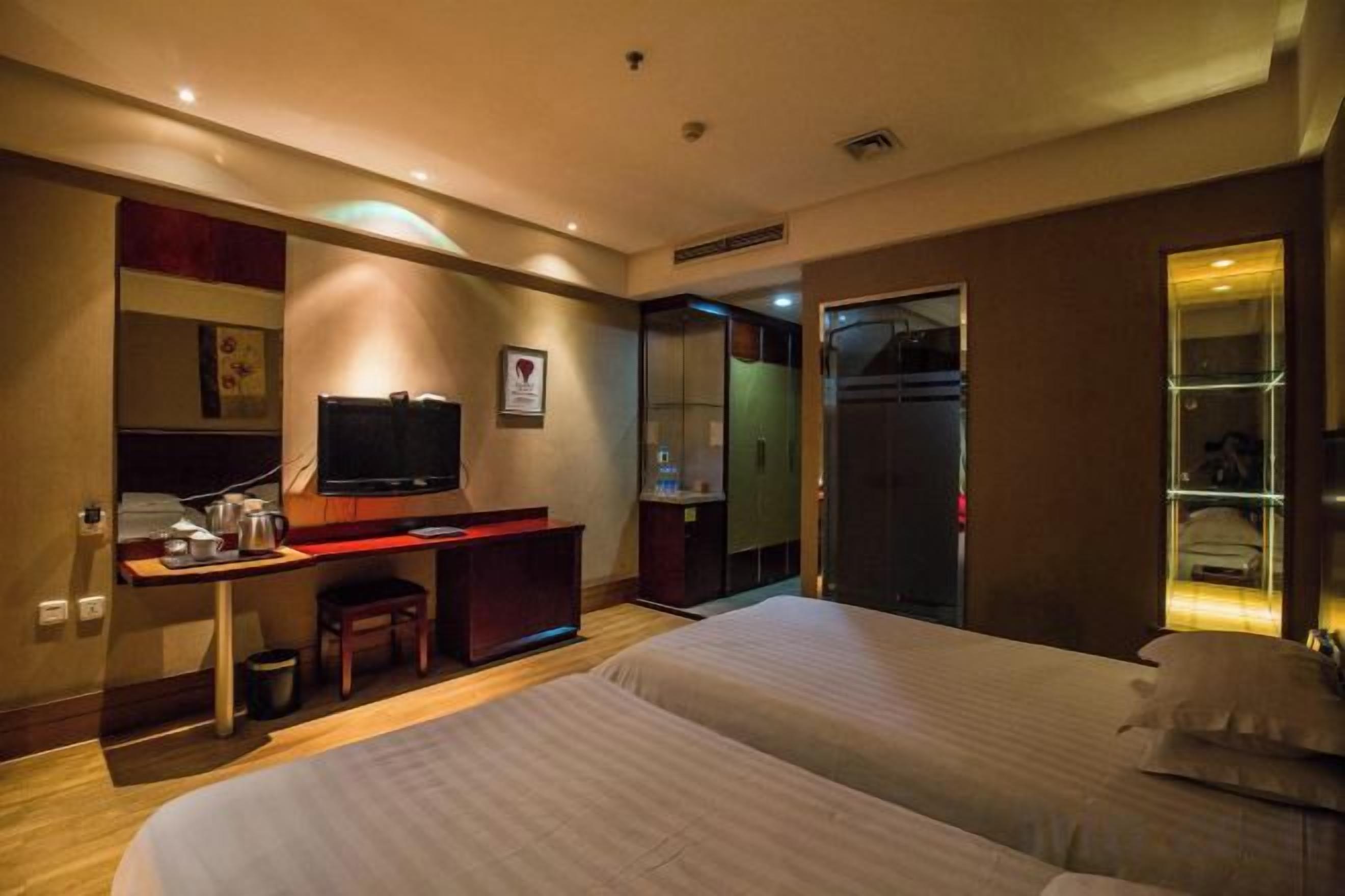 A hotel room with a bed, desk, television, and a mirror.