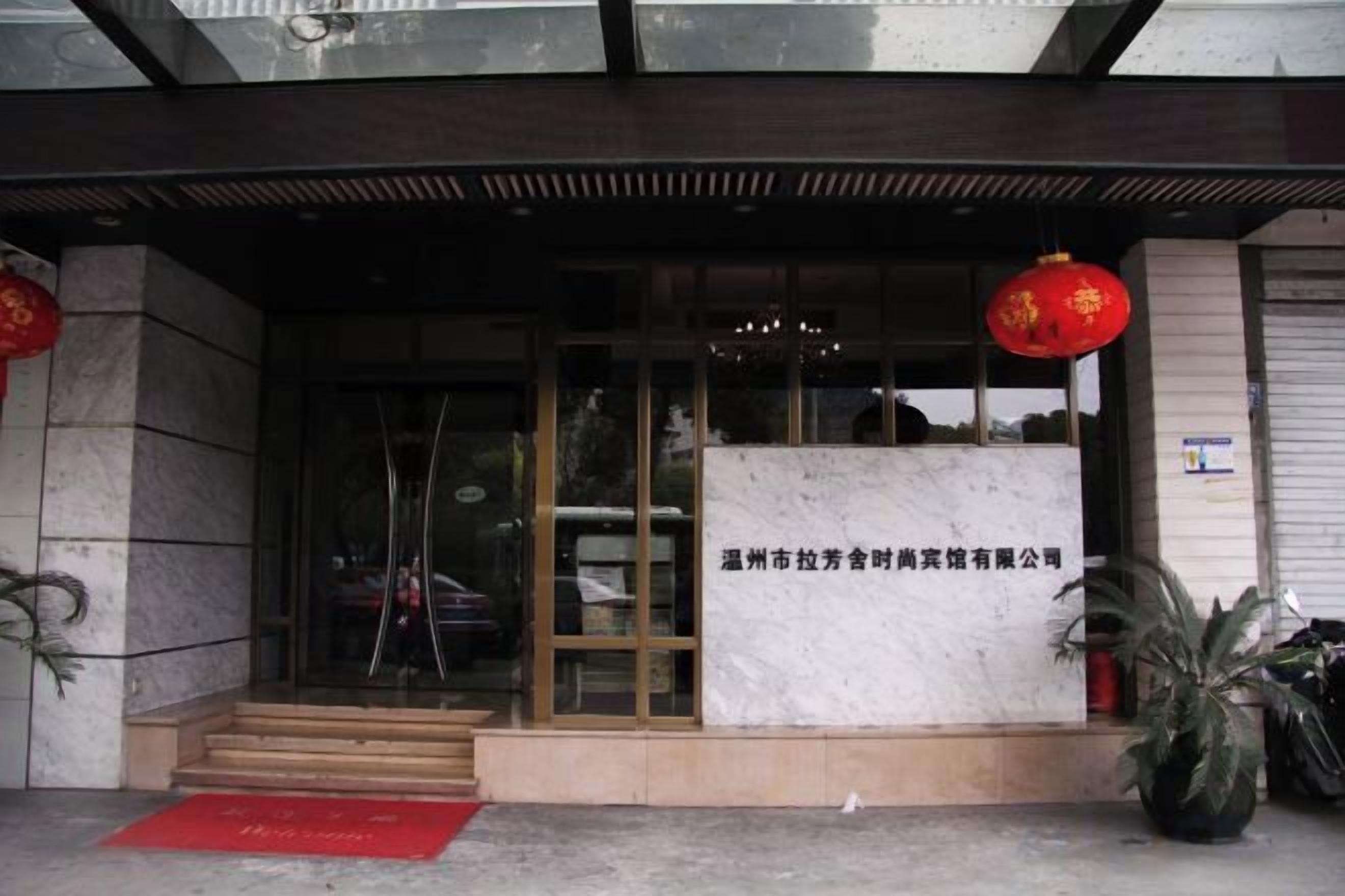 A hotel entrance with a glass door, a red lantern, and a signboard.