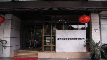 A hotel entrance with a glass door, a red lantern, and a signboard.