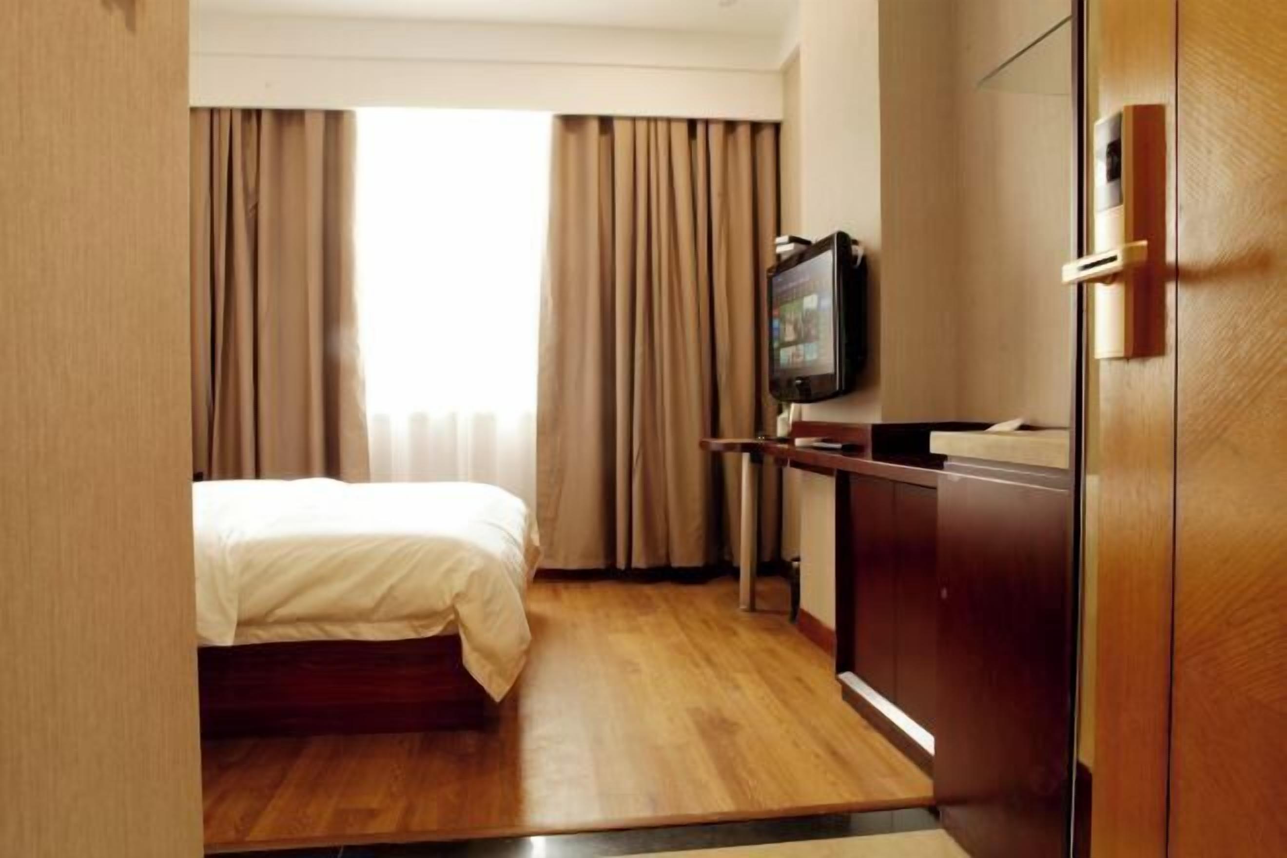 Ein Hotelzimmer mit Bett, Schreibtisch, Fernseher und Kleiderschrank.
