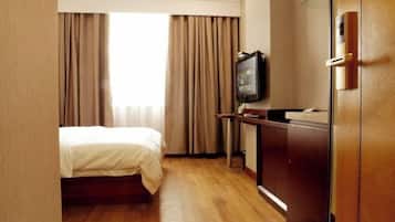 Ein Hotelzimmer mit Bett, Schreibtisch, Fernseher und Kleiderschrank.