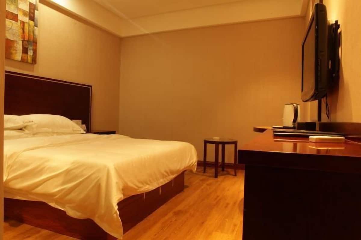 Una habitación de hotel con una cama, una mesita, un escritorio y un televisor en la pared.