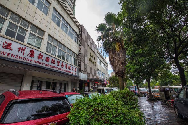 A street with parked cars and a building with a sign in a foreign language.