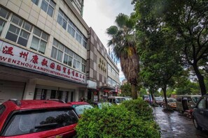 A street with parked cars and a building with a sign in a foreign language. - Lafangshe Fashion Hotel (Wenzhou)