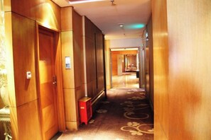 A hotel hallway with wooden doors, a red luggage cart, and a patterned carpet. - Lafangshe Fashion Hotel (Wenzhou)