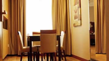 Un coin repas avec une table et des chaises, des rideaux beiges et un tableau au mur.