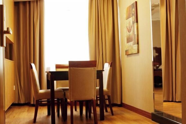 A dining area with a table and chairs, beige curtains, and a painting on the wall. - Lafangshe Fashion Hotel (Wenzhou)