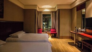 Une chambre d’hôtel avec deux lits, un bureau, une chaise et un téléviseur.