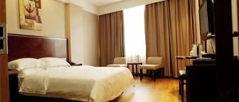 Hotelkamer met een bed, bureau, stoel, televisie en raam met gordijnen.