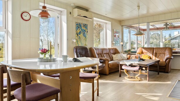Un salon lumineux, avec une table à manger en bois, des fauteuils en cuir et un canapé.