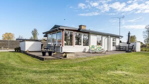 Une maison de plain-pied dotée d’un patio couvert, d’une petite terrasse et d’une pelouse.