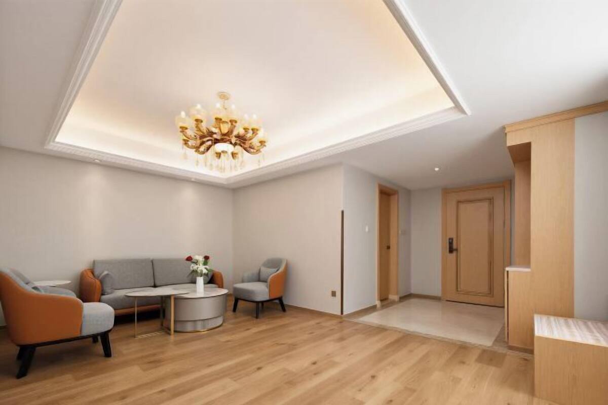 A modern living room with a ceiling light fixture, a sofa, two armchairs, and a coffee table.