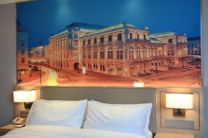 Habitación de hotel con una cama grande, dos lámparas de noche y un teléfono en la pared.