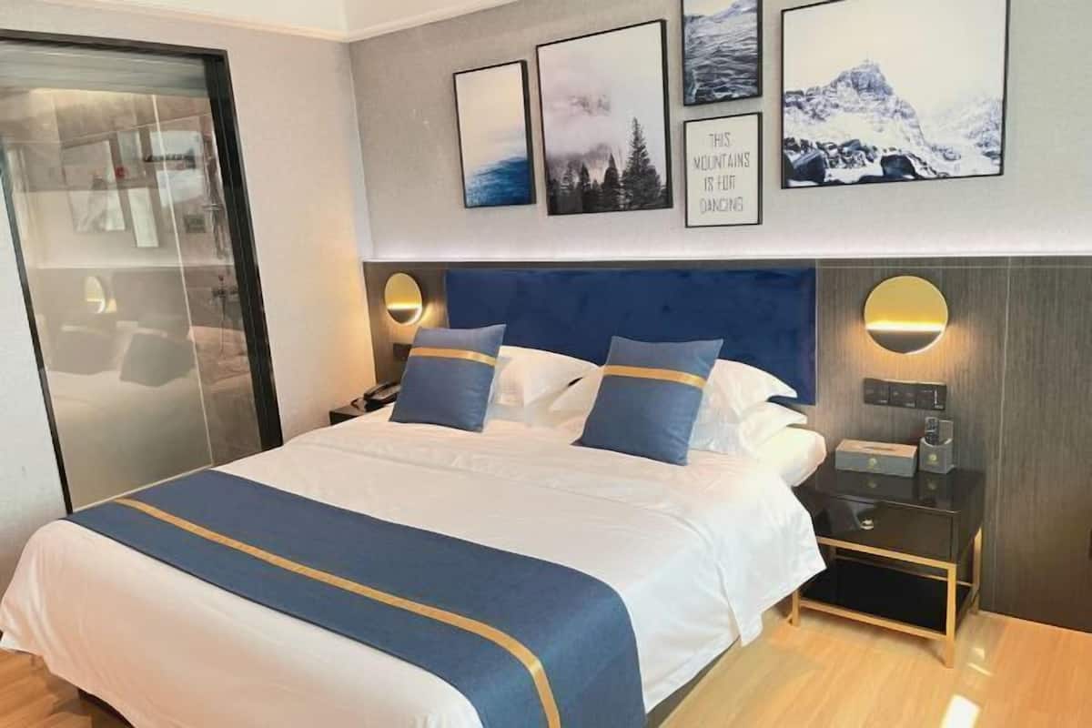 Una habitación de hotel con una cama, mesitas de noche y una obra de arte en la pared.