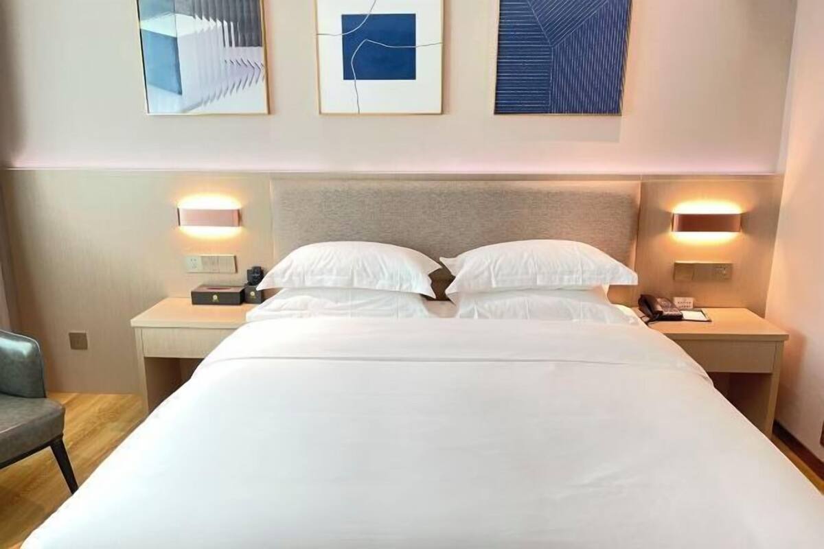 Una habitación de hotel con una cama grande, dos mesitas de noche y lámparas fijadas a la pared.