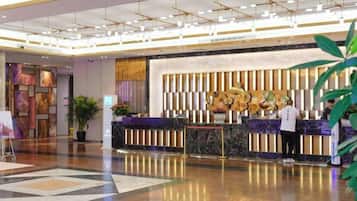 A hotel reception area with a modern design, a reception desk, and a large plant.