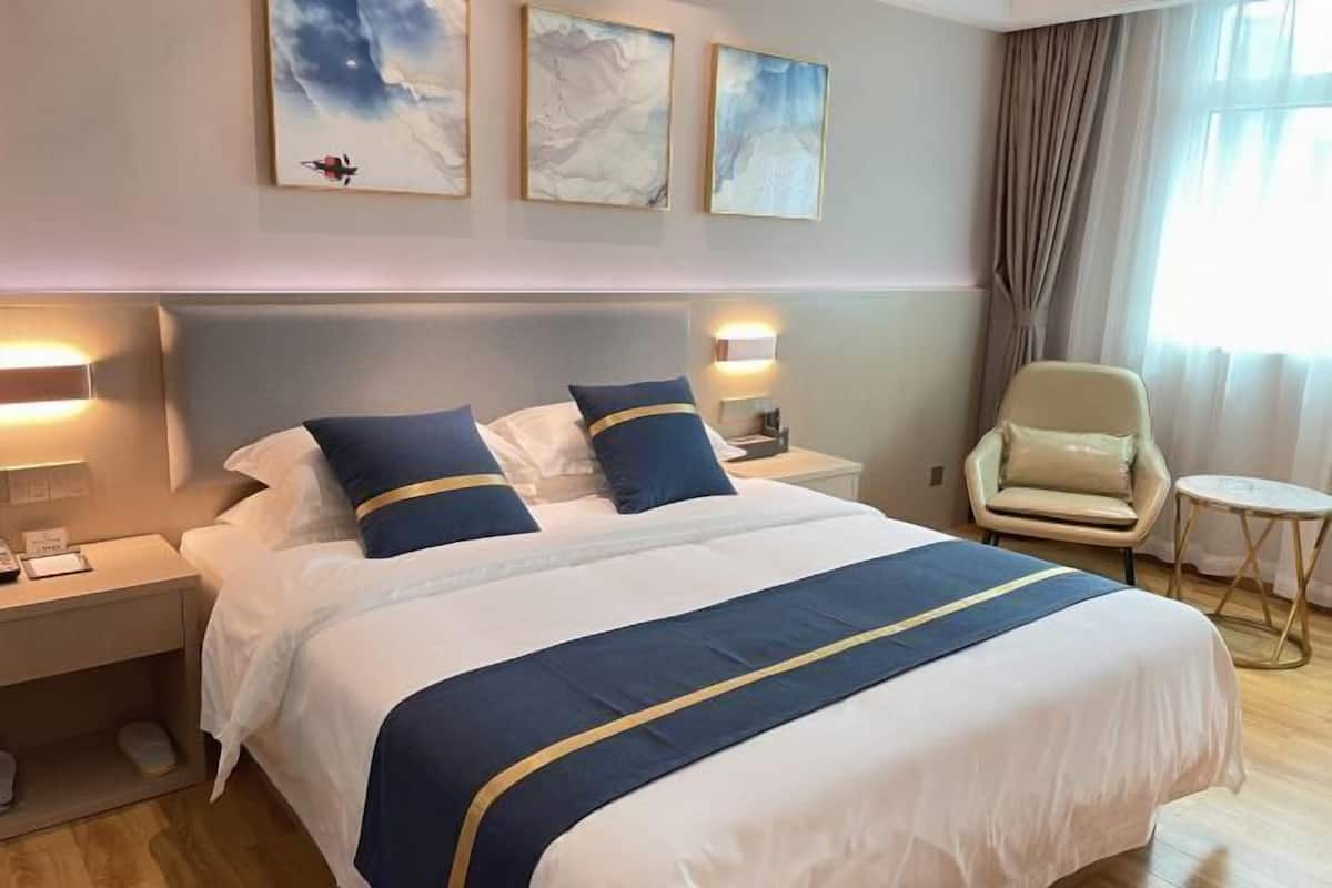 Una habitación de hotel con una cama grande, dos mesitas de noche, una silla y una pequeña mesa.