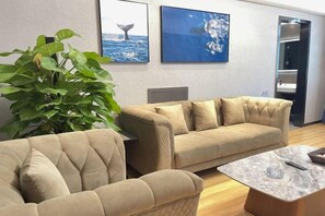 Uma sala de estar moderna com dois sofás bege, uma mesa de centro e uma grande planta verde.
