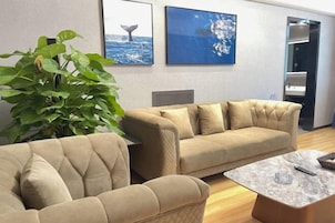 A modern living room with two beige sofas, a coffee table, and a large green plant.