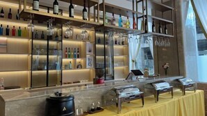 Una zona de bar con estantes llenos de botellas y vasos, una encimera de mármol y un mantel amarillo.