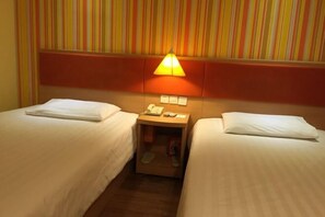 A hotel room with two single beds, a nightstand with a lamp, and a striped wall. - Hemei Rujia Express Hotel (Fukang)