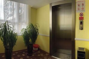 An elevator with a control panel and a wall-mounted sign. - Hemei Rujia Express Hotel (Fukang)