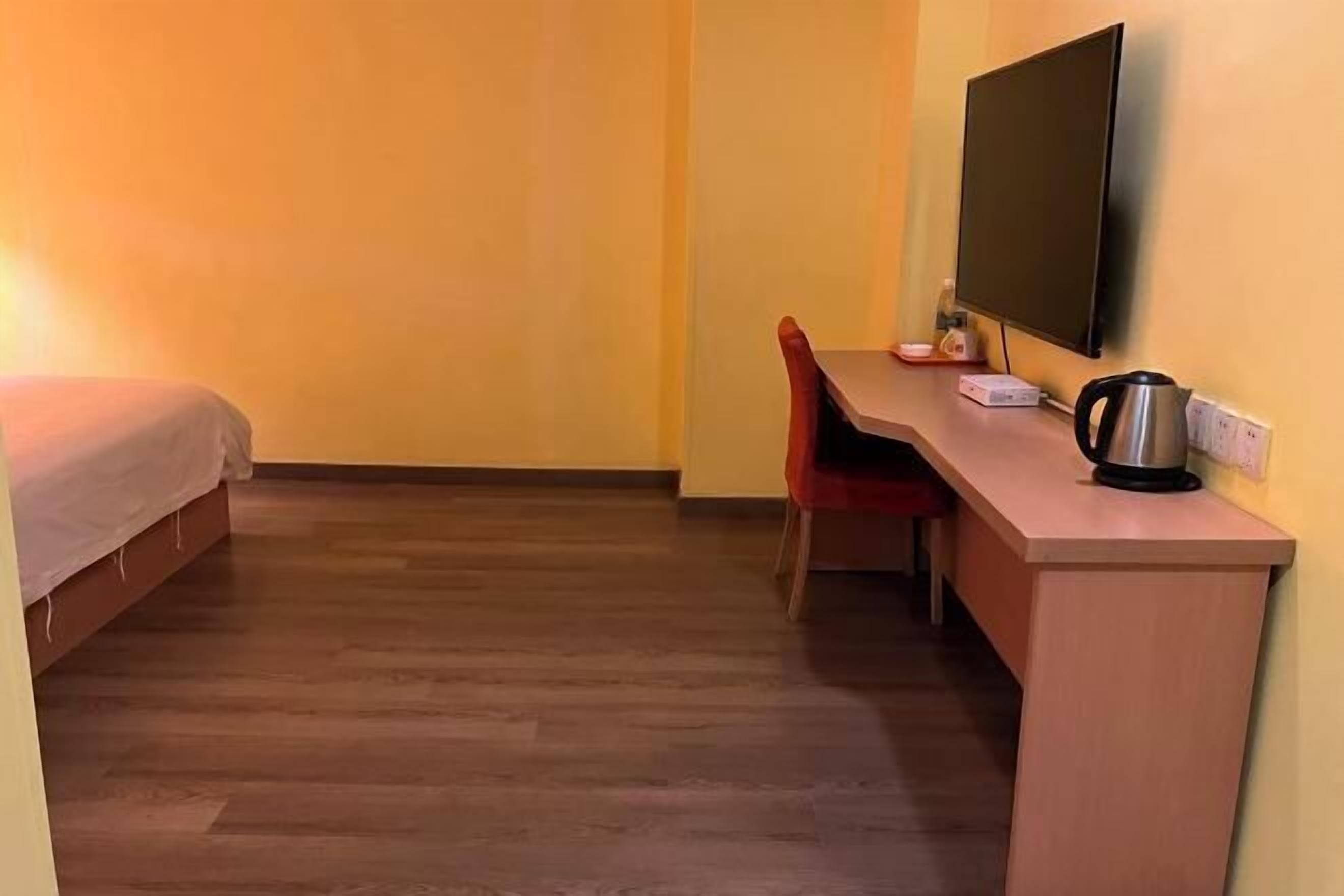 Pieni huone, jossa on sänky, työpöytä, tuoli, televisio ja vedenkeitin.