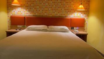 A hotel room with a large bed, two bedside tables, a telephone, and a wall with a polka dot pattern.