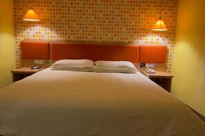 A hotel room with a large bed, two bedside tables, a telephone, and a wall with a polka dot pattern. - Hemei Rujia Express Hotel (Fukang)