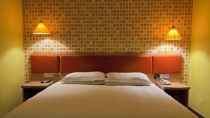 Ein Hotelzimmer mit Bett, zwei Nachttischen, einem Kopfteil und Tapete mit Punkten.