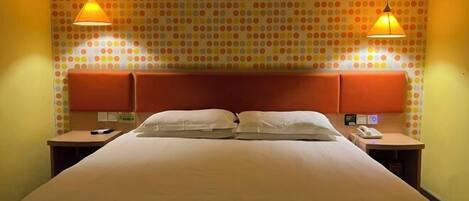 A hotel room with a bed, two bedside tables, a headboard, and a polka dot wallpaper.