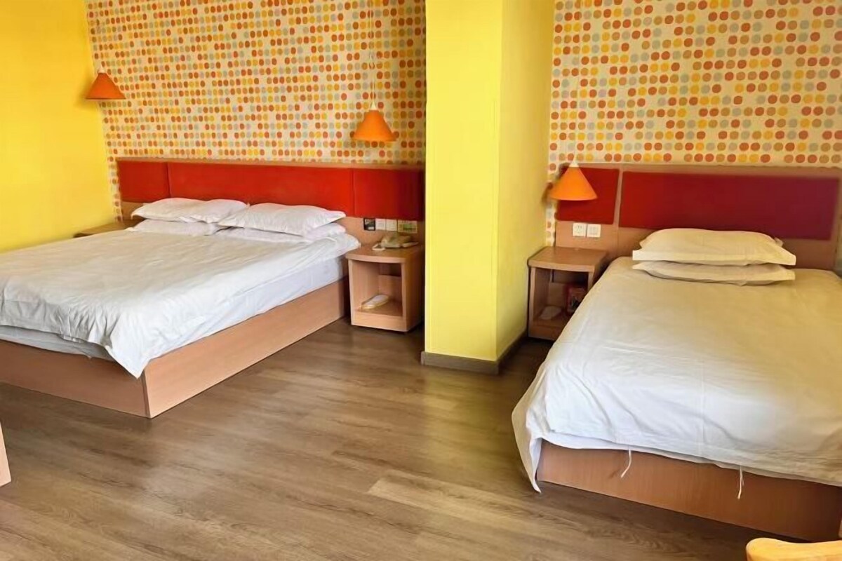 A hotel room with two beds, wooden flooring, and a polka dot wallpaper.
