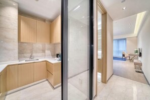 A modern kitchen with wooden cabinets, a marble countertop, and a glass partition. - Humgait Hotel (Hangzhou)