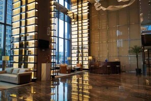 A spacious lobby with a reflective floor, a reception desk, and seating areas. - Humgait Hotel (Hangzhou)