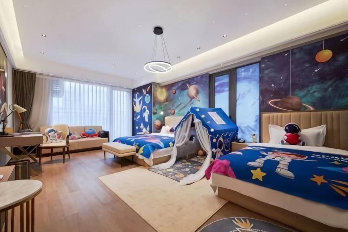 A hotel room with two beds, a desk, a chair, and a large window.