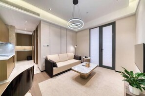 A modern living room with a sofa, coffee table, and a potted plant. - Humgait Hotel (Hangzhou)