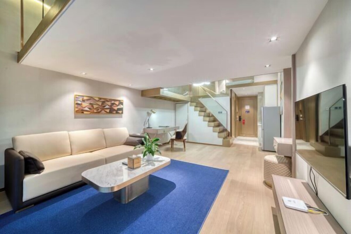 A modern living room with a sofa, coffee table, and a flat-screen TV.