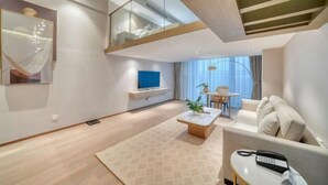 A modern living room with a sofa, coffee table, and a TV. - Humgait Hotel (Hangzhou)