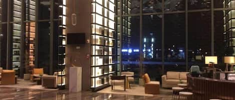 A spacious lobby with a high ceiling, a reception desk, and seating areas.