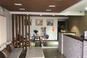Un espace d’accueil comprenant un comptoir de réception, un coin salon et une cloison en bois.