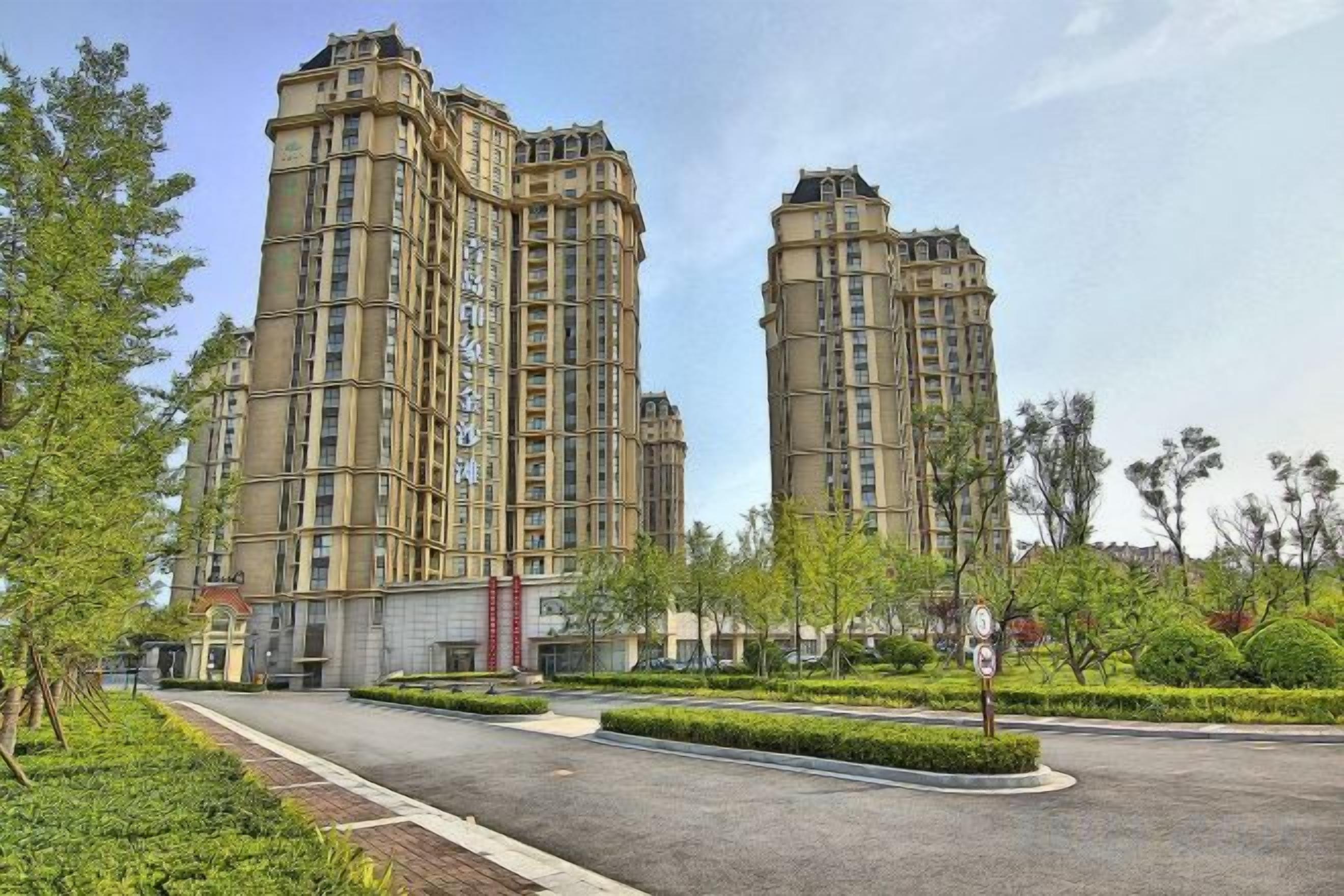 A high-rise residential building with a central courtyard and surrounding greenery.