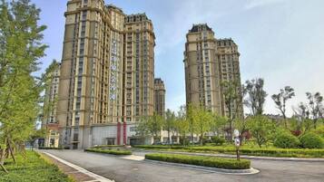 A high-rise residential building with a central courtyard and surrounding greenery.