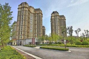 Edifício residencial alto com pátio central e áreas verdes ao redor.