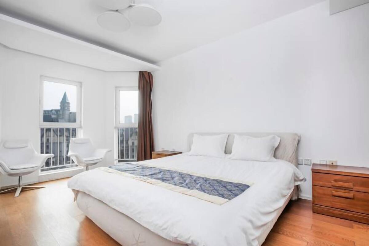 Une chambre d’hôtel moderne avec un grand lit, une commode en bois, un bureau et deux chaises.