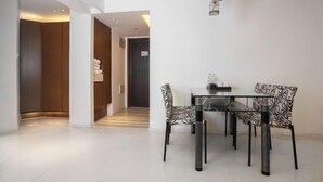 A modern dining area with a glass table and patterned chairs, a wooden door, and a hallway leading to another room.