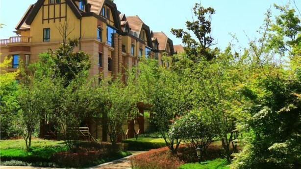 A multi-story building with a traditional architectural style, surrounded by well-maintained gardens and a pathway.