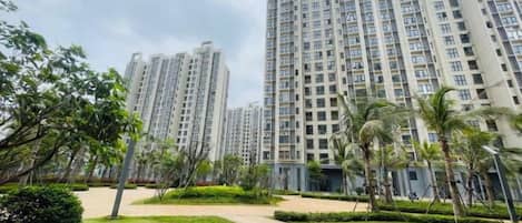 A residential building complex with multiple high-rise apartments, a well-maintained lawn, and a clear sky.
