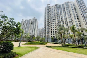 A residential building complex with multiple high-rise apartments, a well-maintained lawn, and a clear sky. - Haikou Lin's House Holiday Seaview Homestay (Haikou)