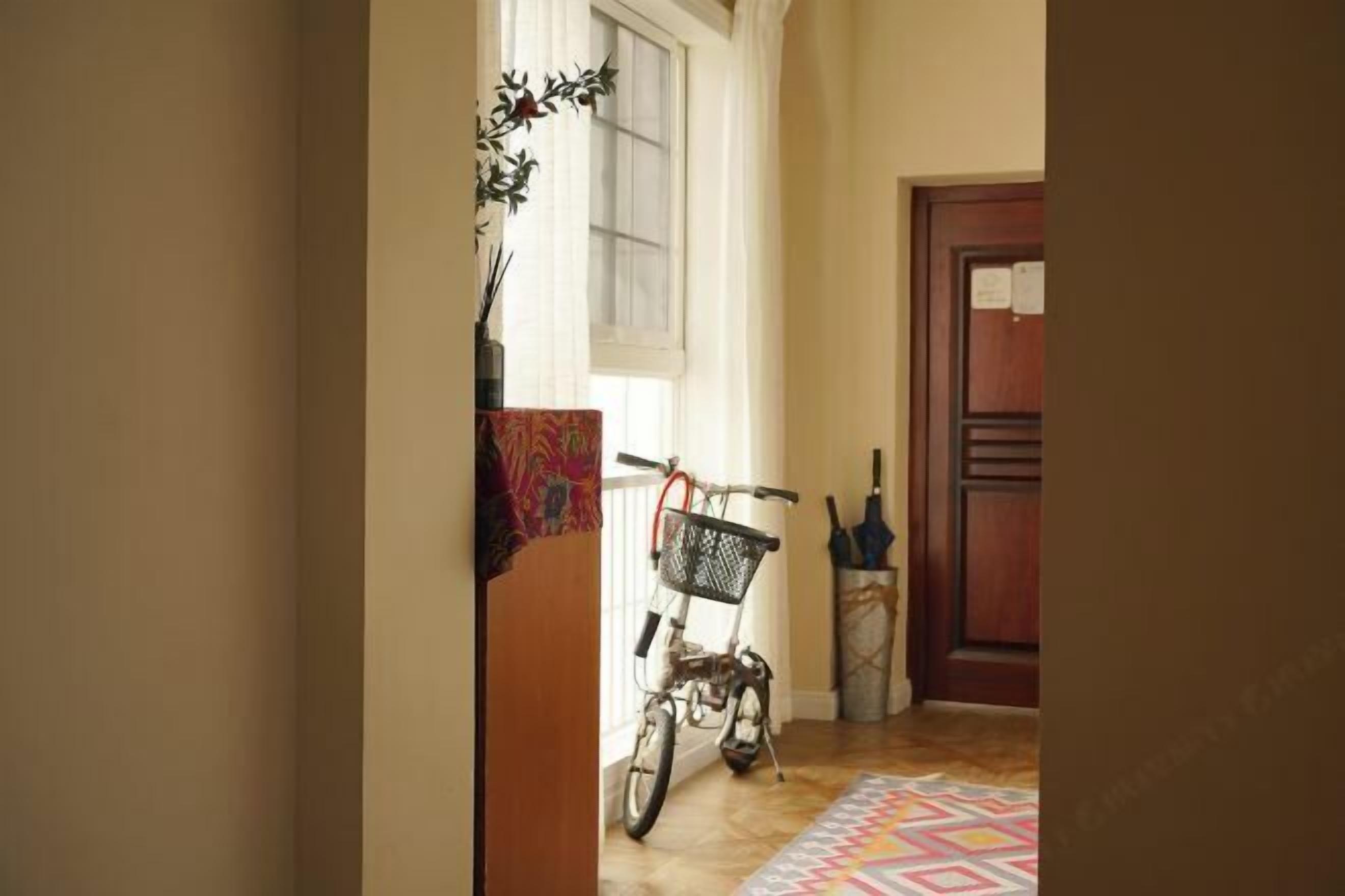 Un pasillo con una bicicleta, un tapete estampado y una puerta de madera.